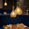 DECANTER amber glass pendant lights clustered over restaurant booth
